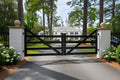 Wooden gate at the entrance of a driveway with a white house in the background