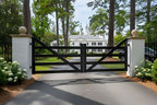 Wooden gate at the entrance of a driveway with a white house in the background