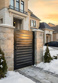 Modern gate in front of a house with snow on the ground